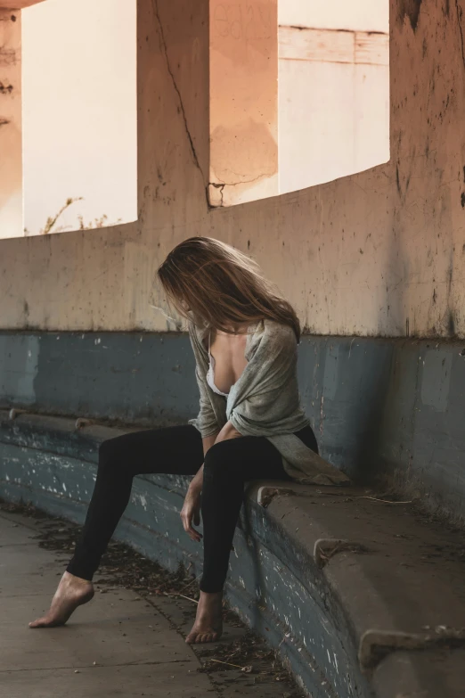 woman in gray shirt sitting on a bench looking at her phone