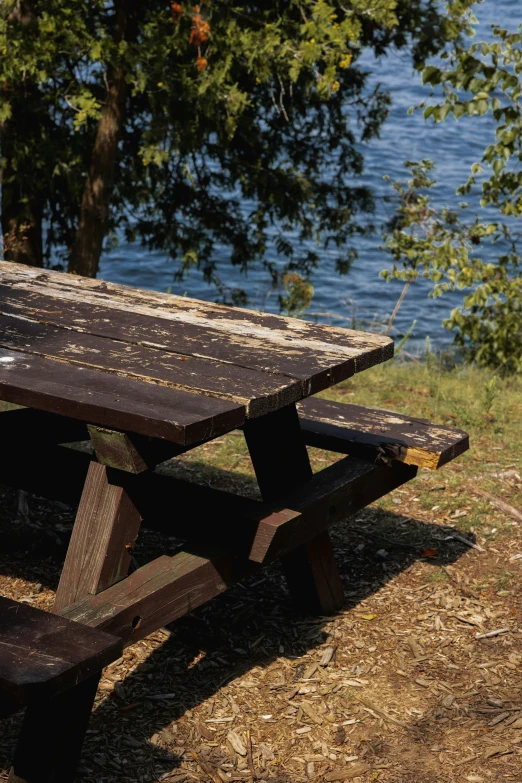 the picnic table has rusted wood and sits on the ground