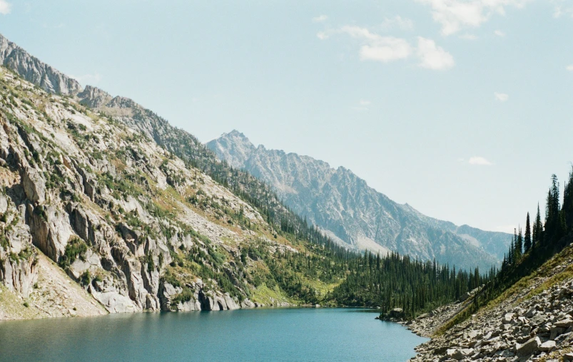 a blue lake surrounded by mountains under a cloudy sky