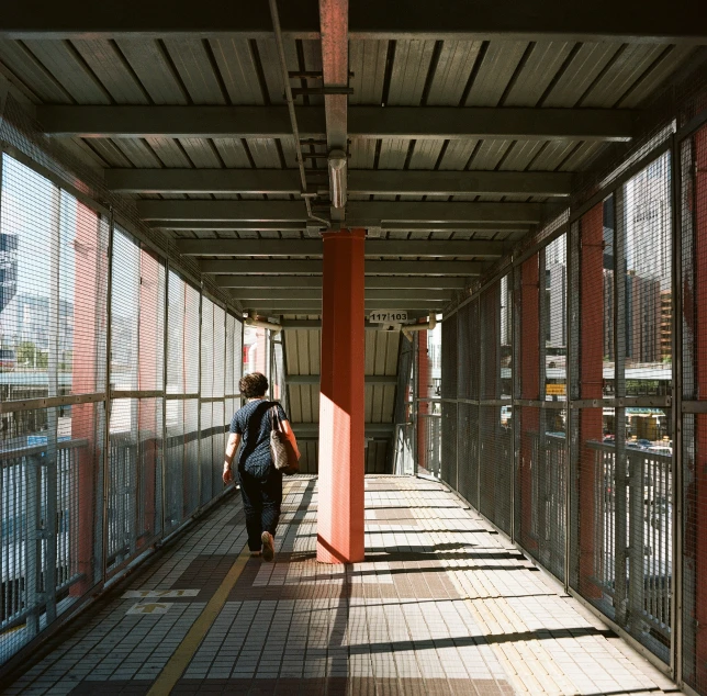 the sidewalk under an overpass has mesh covering it