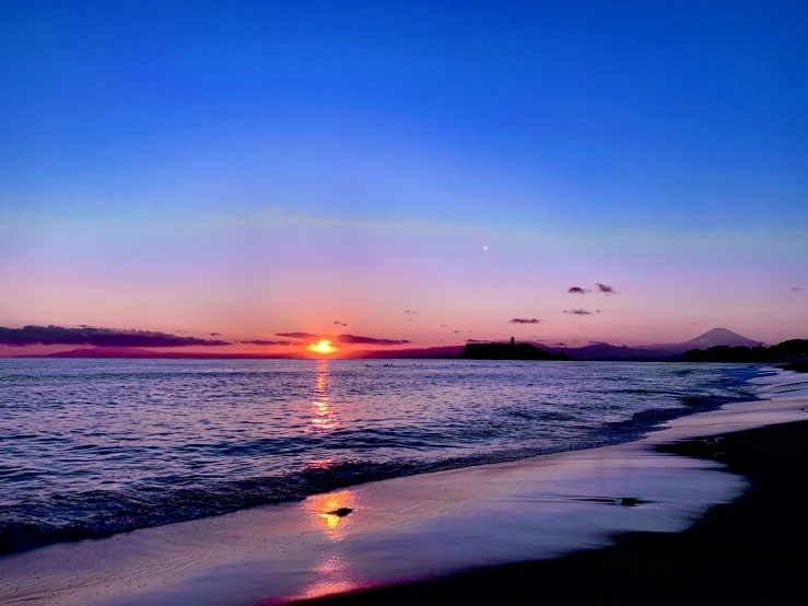 the sun rises behind the horizon of the beach