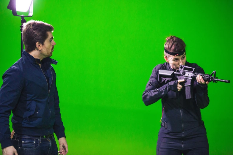 two men on a green screen posing with a gun