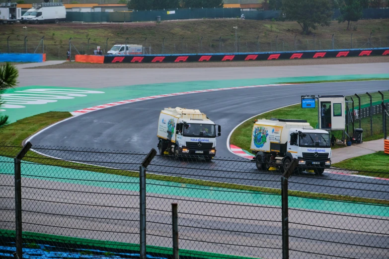 two trucks driving down a racing track next to each other