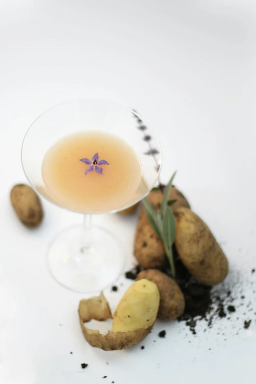 a drink sitting on top of a plate near some potatoes