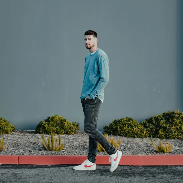 man walking on street in front of grey wall