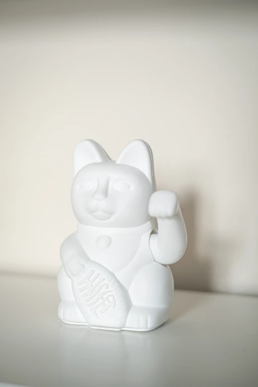 a white cat statue holding an egg on a counter