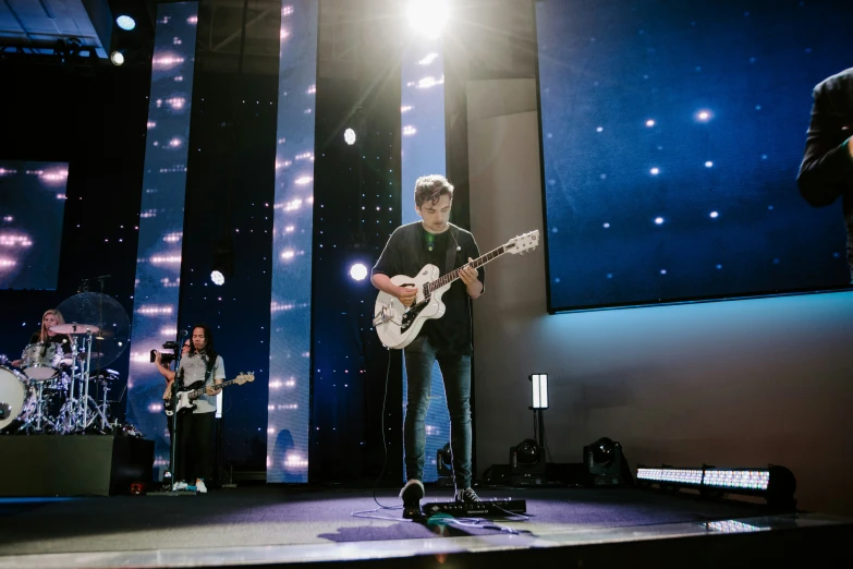 a band performing with a microphone and playing on guitars