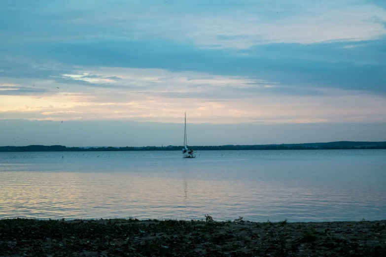 a sailboat floating on the water at dusk