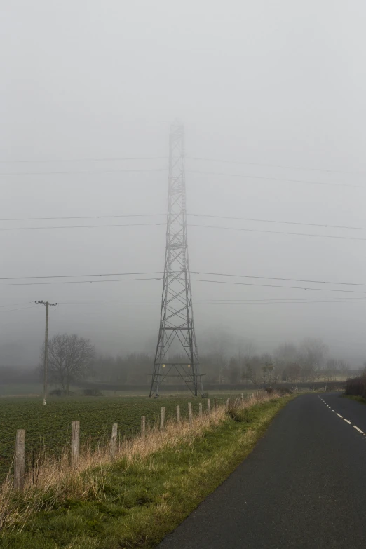 a lonely road is surrounded by power lines in the fog