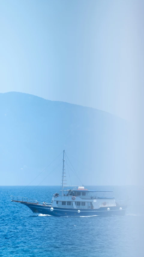 a cruise ship sailing in the ocean near a hill