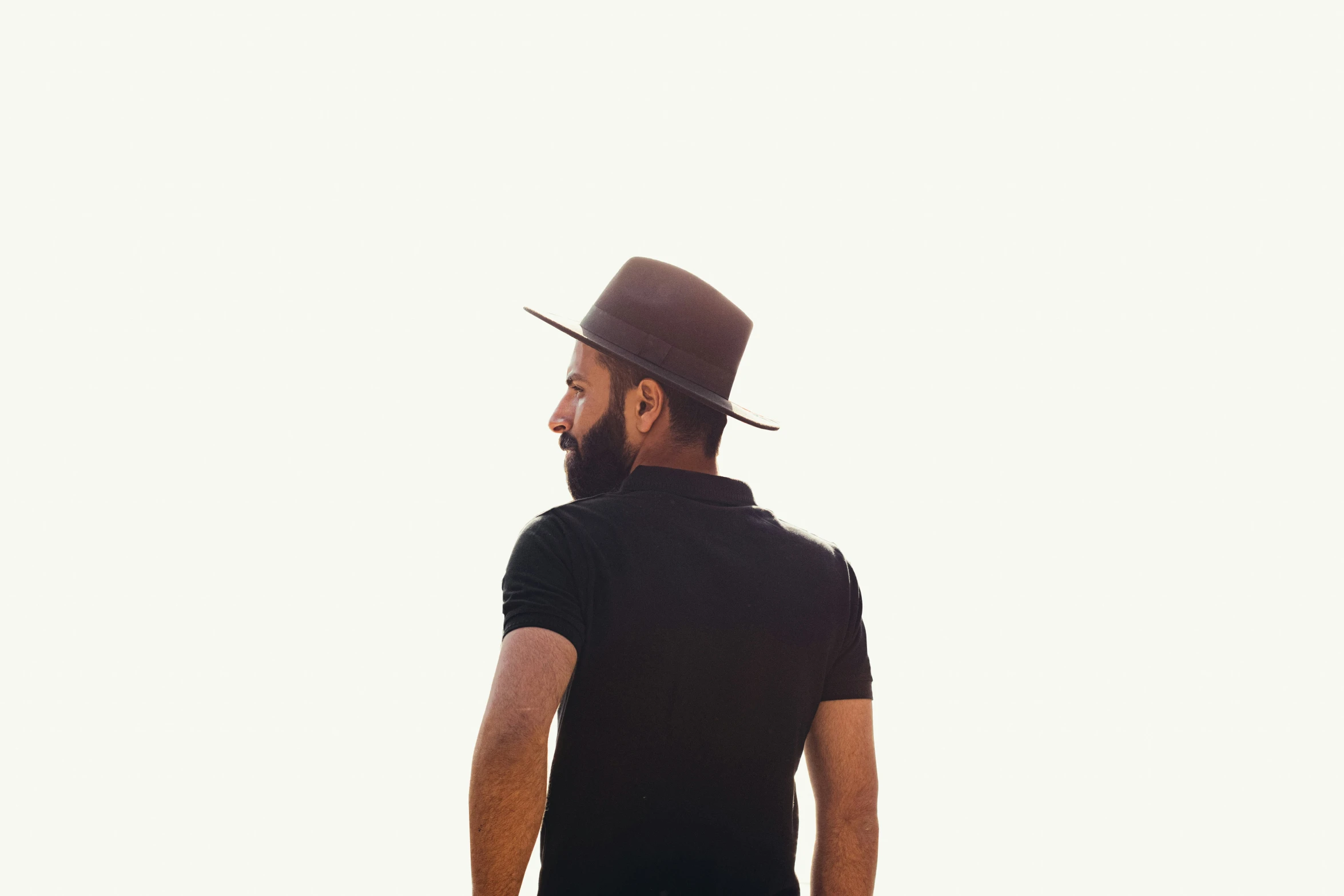 a bearded man with a hat looking off into the distance