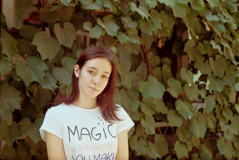 girl with a magic shirt in front of green foliage