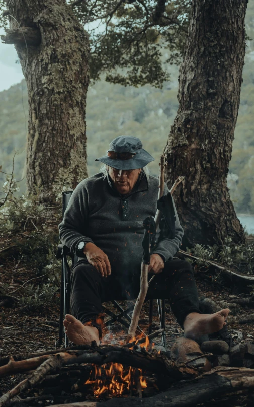 an older man sitting in a chair next to a fire