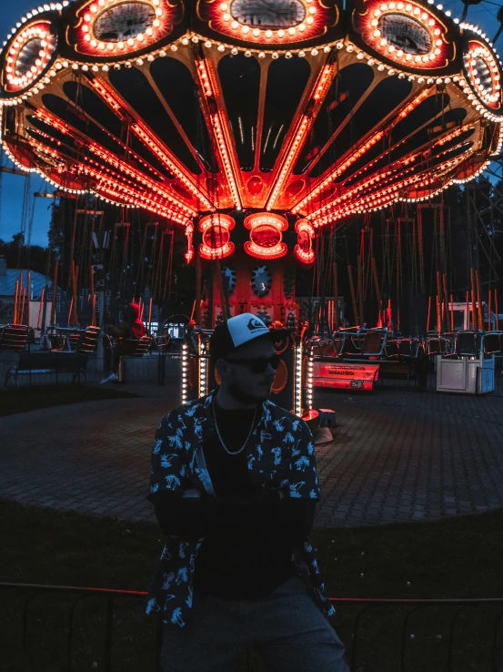 a man sitting on a bench in front of a carnival