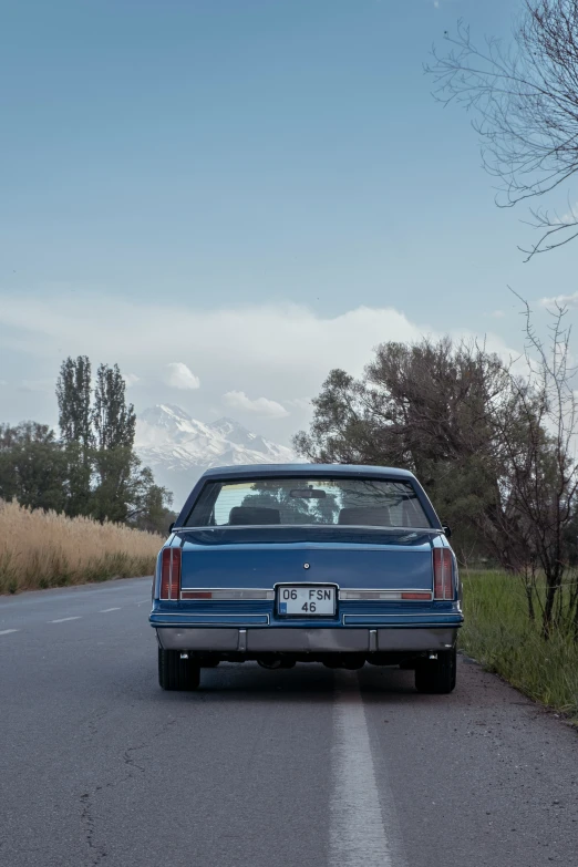 a blue car driving down the road near a hill