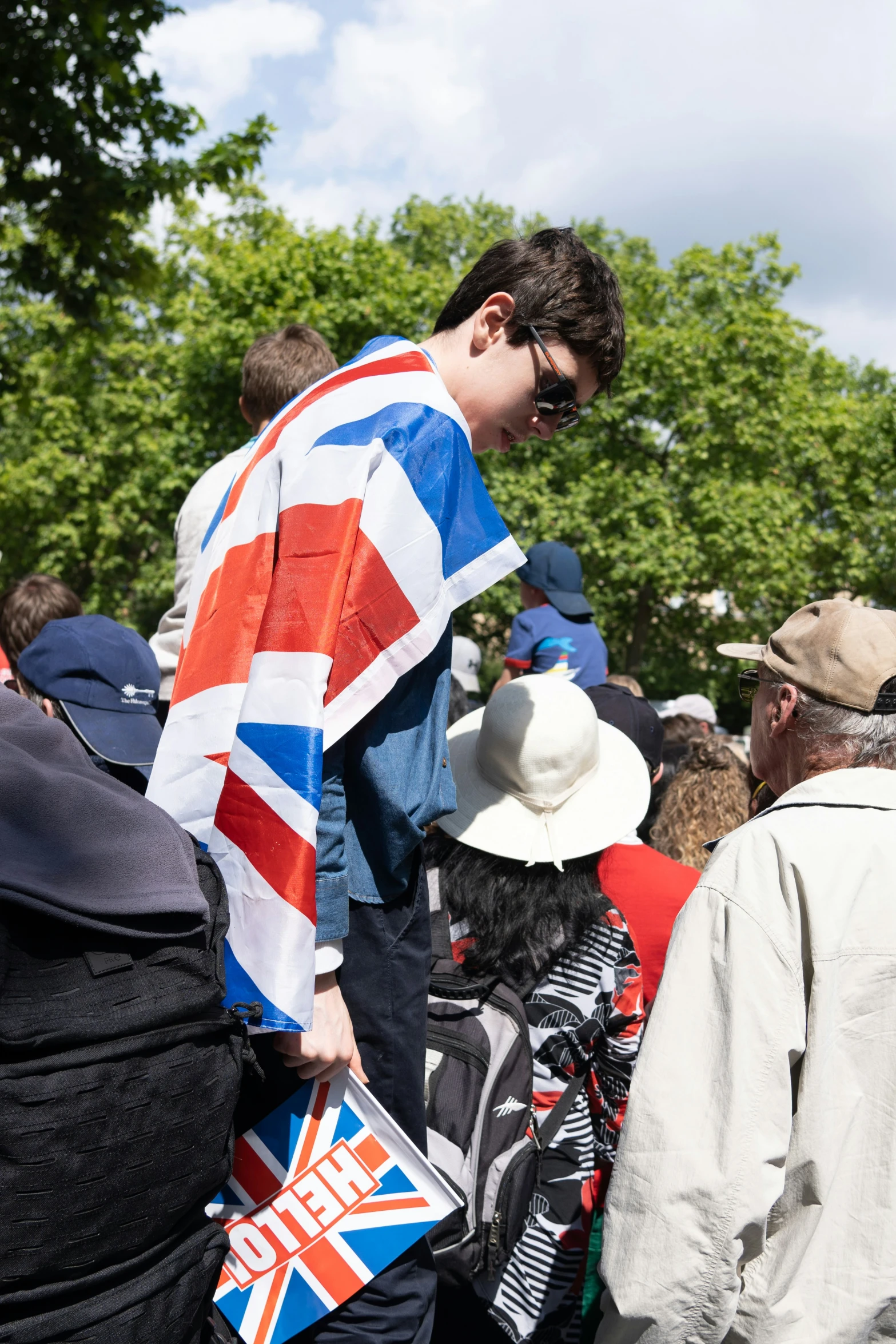 a man standing next to a crowd of people with a british flag jacket on