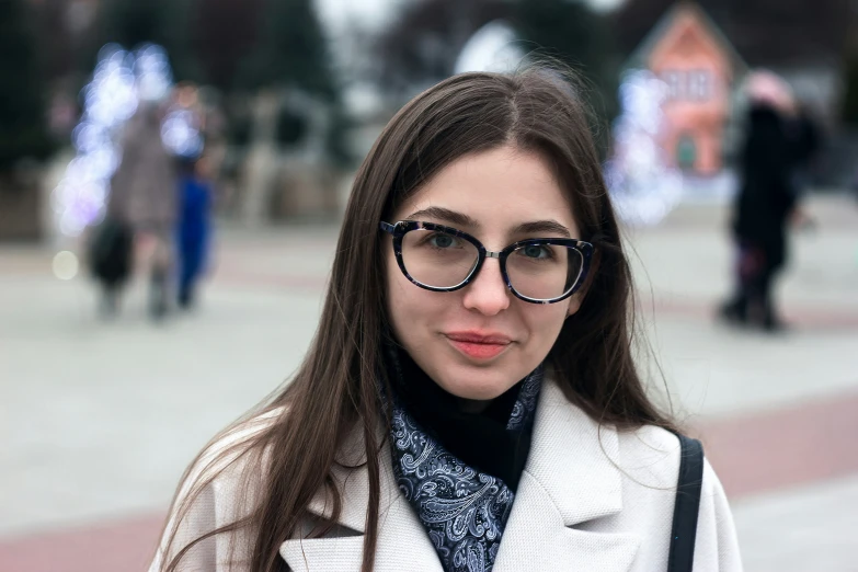 a girl wearing glasses and a scarf standing outside