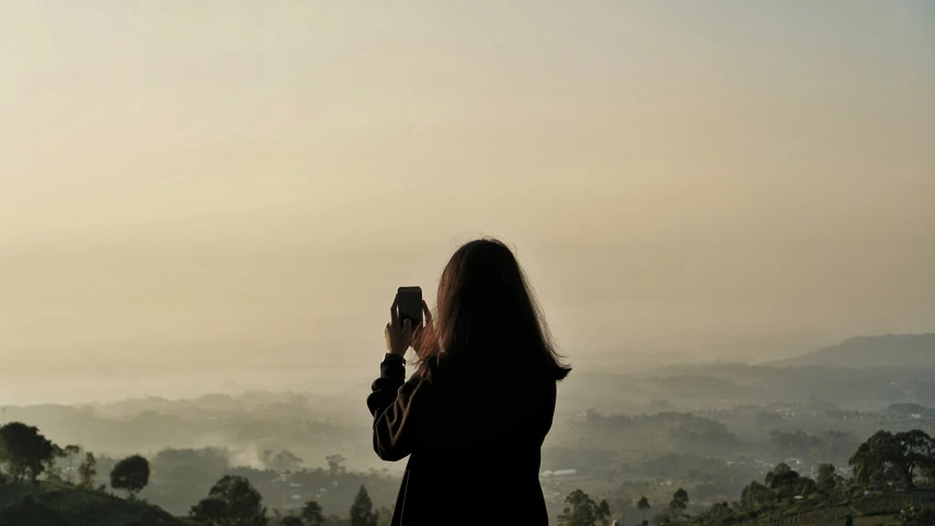 a person taking a picture of the foggy city below