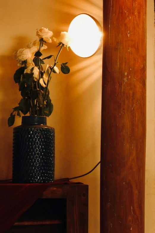 there is a lamp that is on the wall and a vase with roses in it