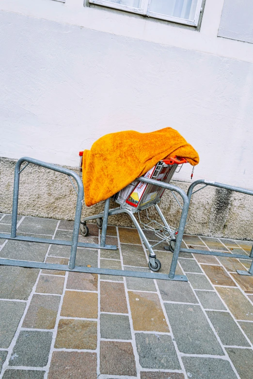 a close up of a small luggage cart with an orange towel on it