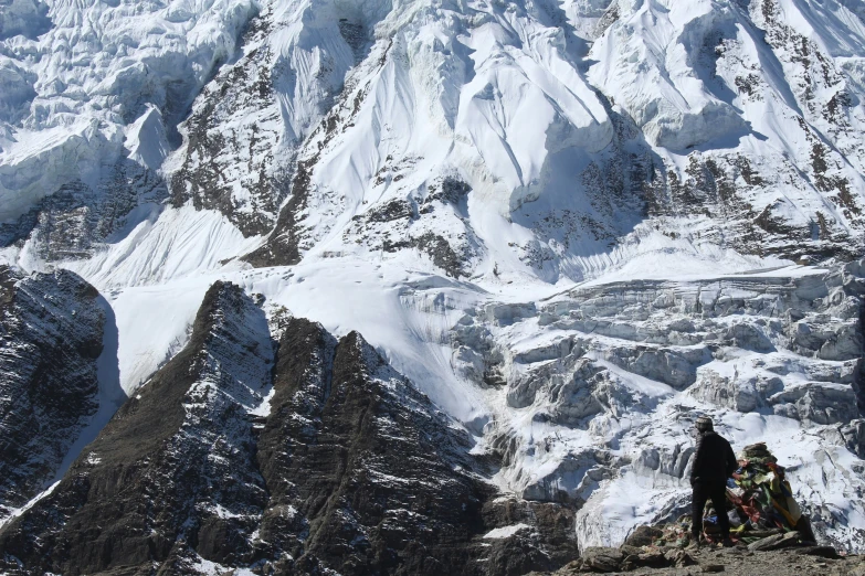 three people with helmets on standing against snowy mountains