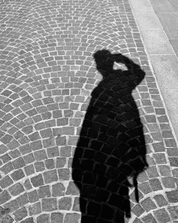 the shadow of a person wearing a hat and holding a camera