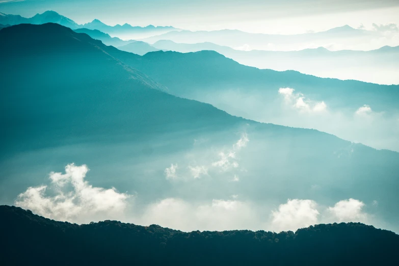 an aerial view of clouds over mountains and valleys