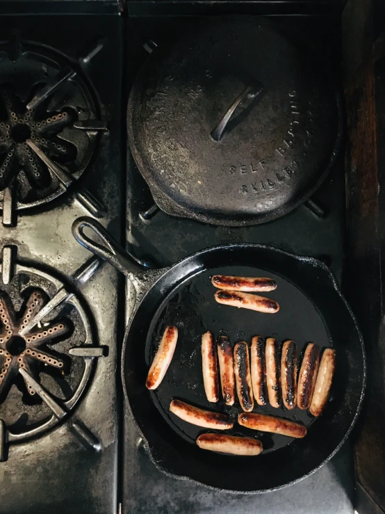 an outdoor grill with  dogs and frying pans