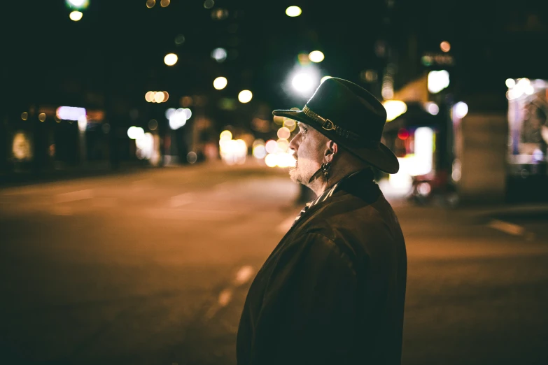 a man standing in front of a street with a green hat