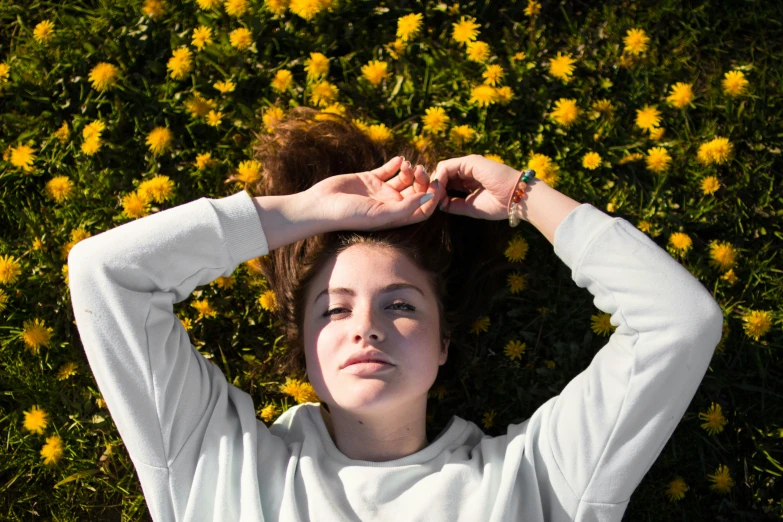 a woman with her hair up and eyes closed standing on some daisies