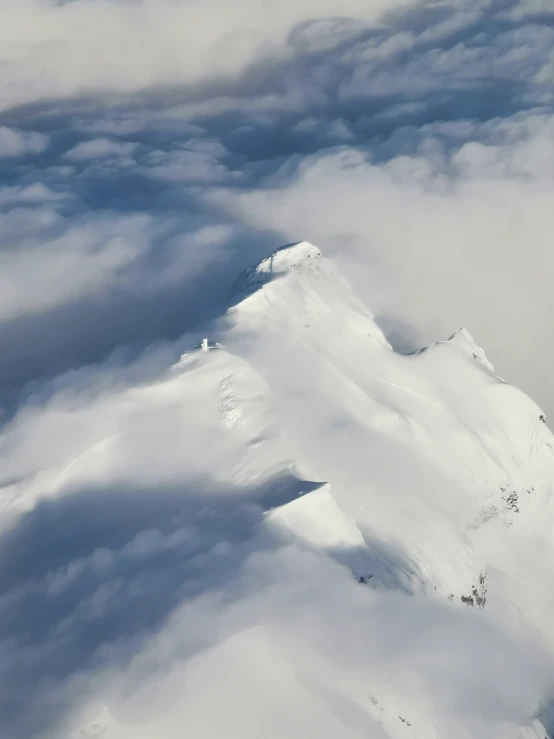 a snowy mountain range in the clouds from an air plane