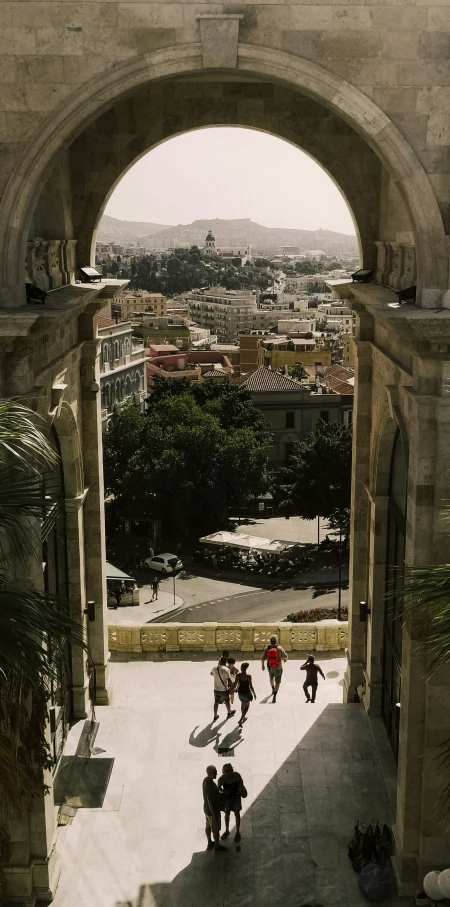 people walk under an arch on the side of a wall