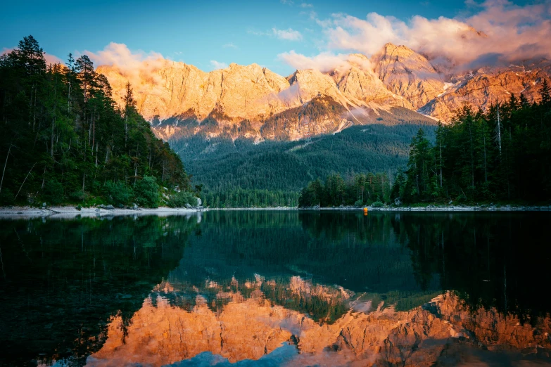 the mountains and trees are reflecting in the lake