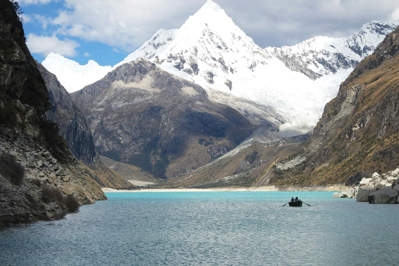 a boat on the side of a river near mountains