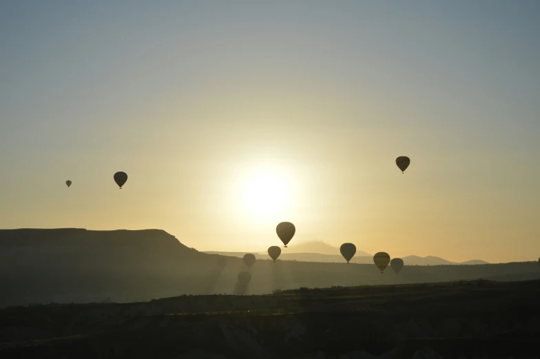 the sun is rising over a hill top