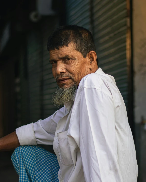 an older man is sitting in front of the door of his home