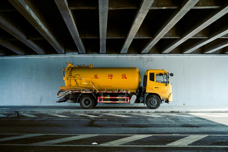 a yellow truck parked underneath an overpass on a city street