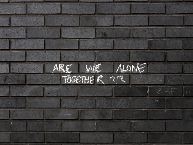 white writing on a black brick wall with white paint