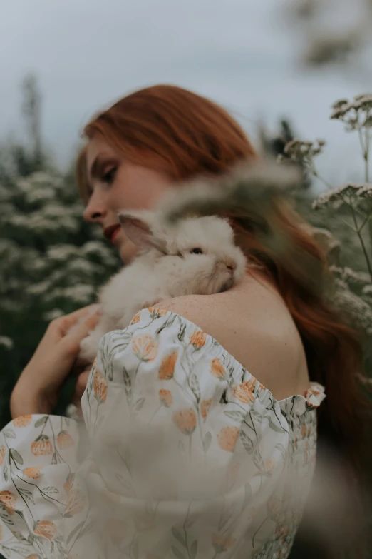 a woman holds a rabbit inside a field of grass