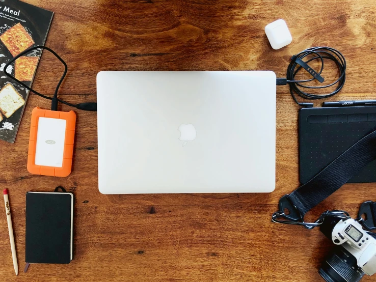a computer, camera and book all laid out on the table