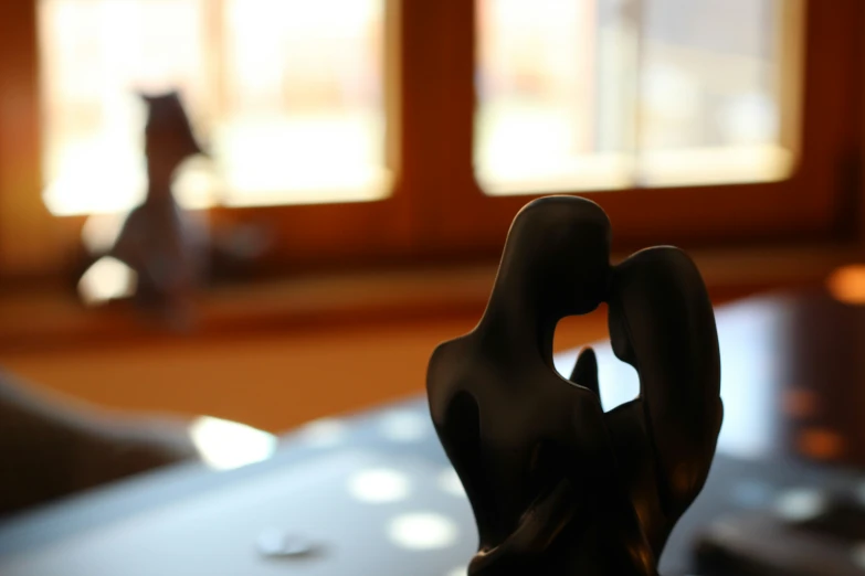 a black statue is sitting near two windows