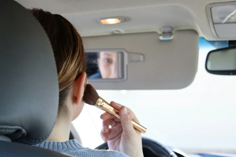 woman in the back seat putting conceal makeup on