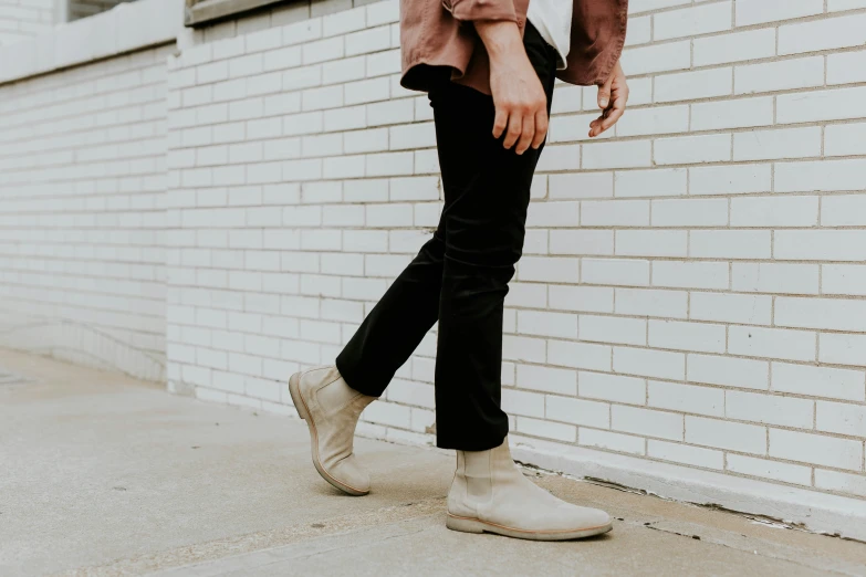 a man in boots walking past a white wall