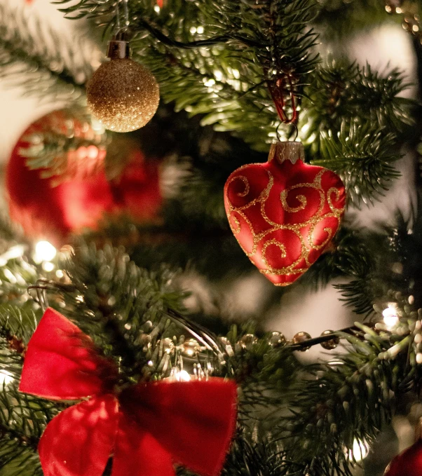 a red heart hanging on a green christmas tree