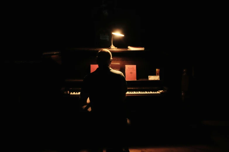 man standing in dark area looking at an upright instrument