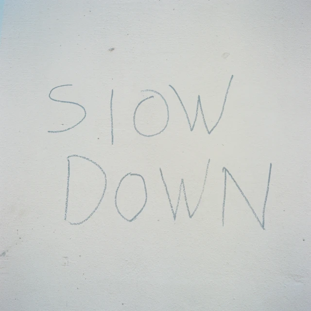 the word slow down is written on a wall