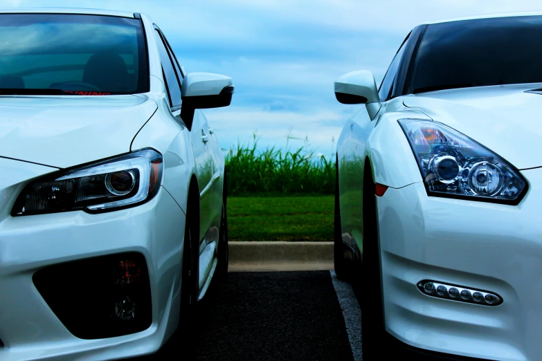 white cars are sitting in a lot with green grass in the background