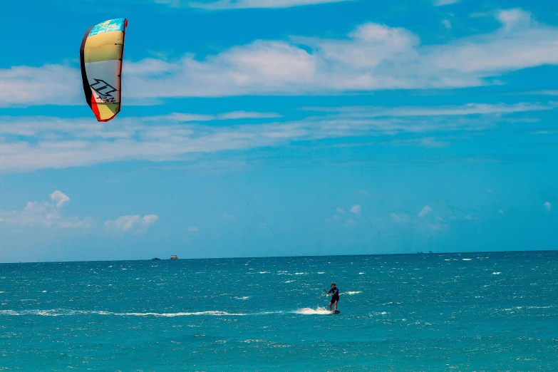 man parasailing on ocean with bright colored sail