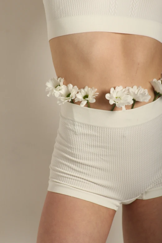 a woman wearing white shorts with flowers in her stomach