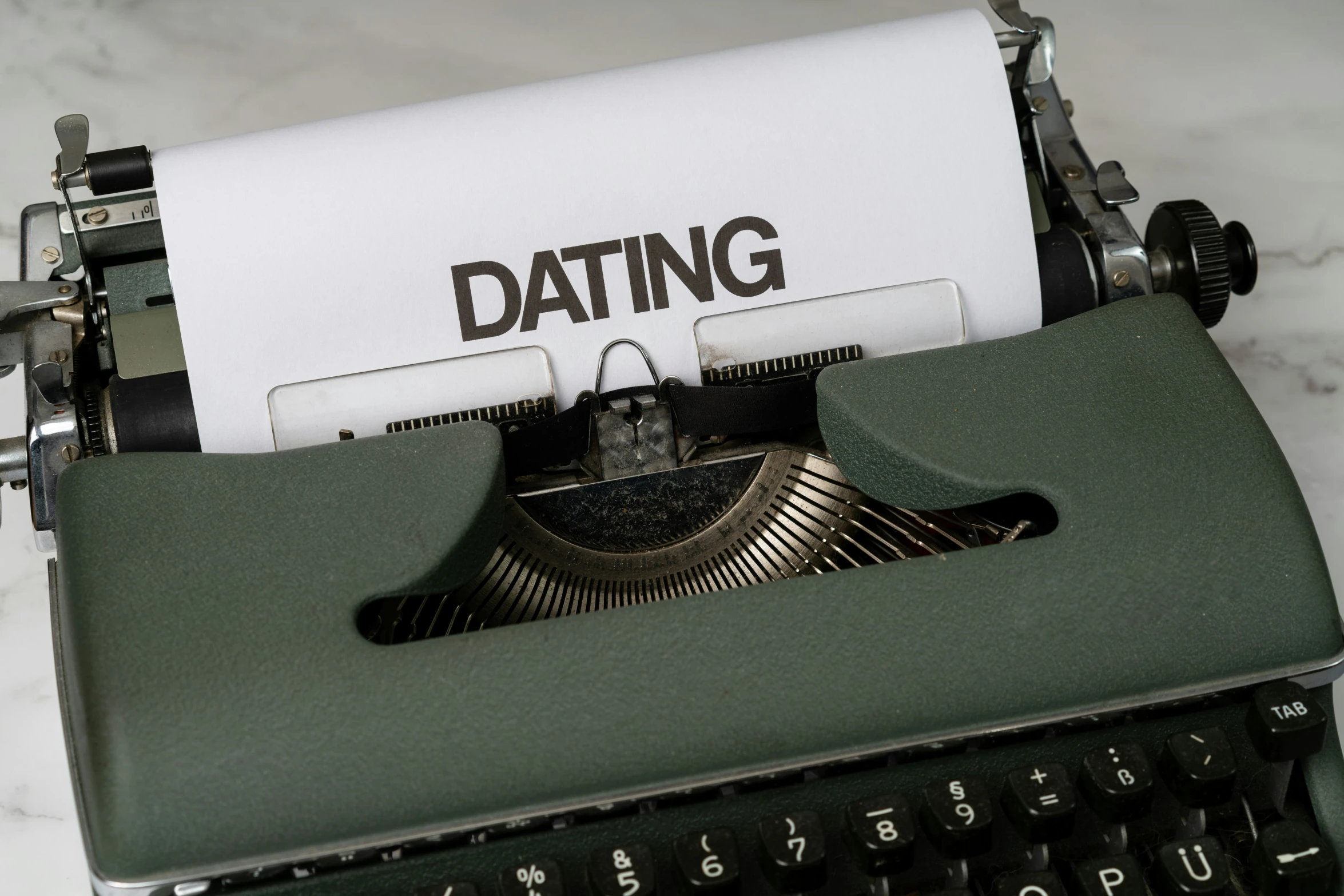 a green old typewriter with the word dating printed on it